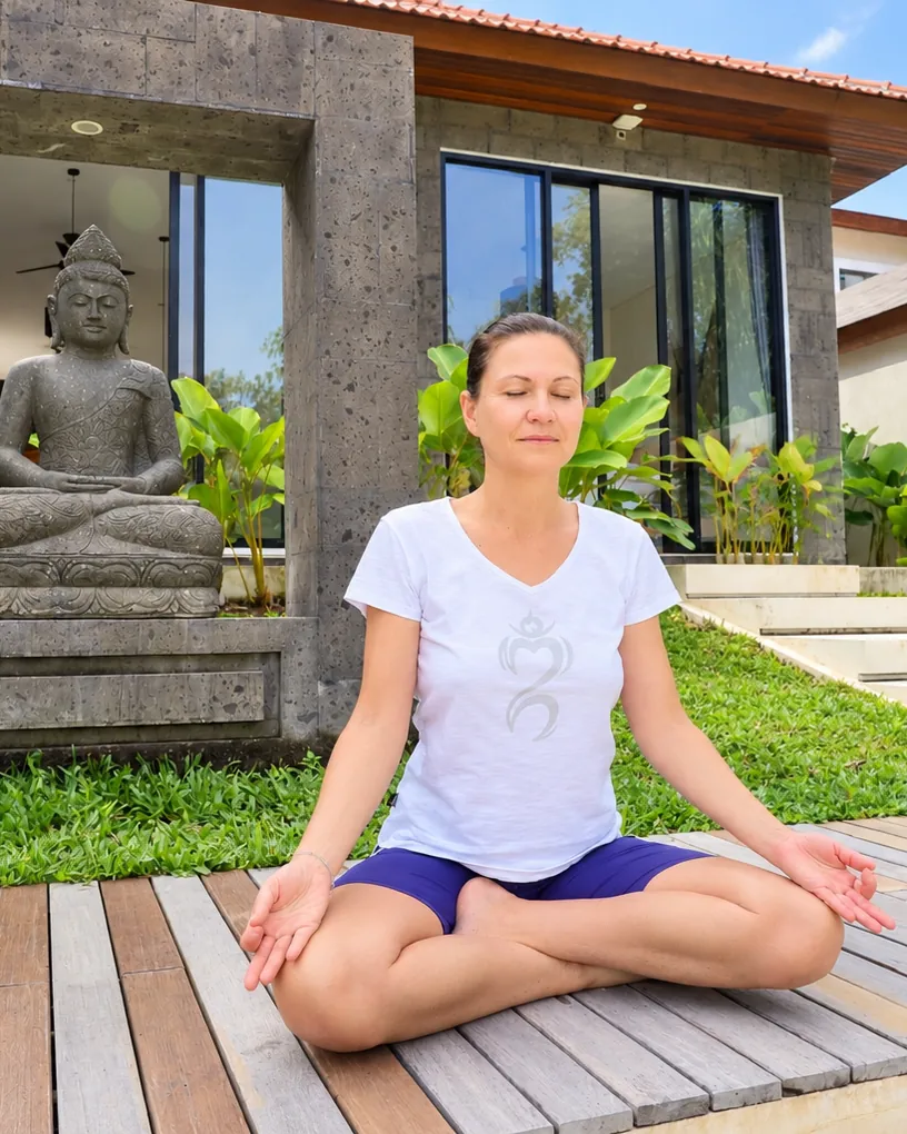 Tina meditiert im Schneidersitz vor einer Buddha-Statue auf Bali